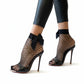 A pair of black mesh fishnet socks with bow designs at the ankle, worn on high heels.