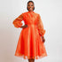 A woman wearing an orange midi dress with pleated and fluffy sleeves.
