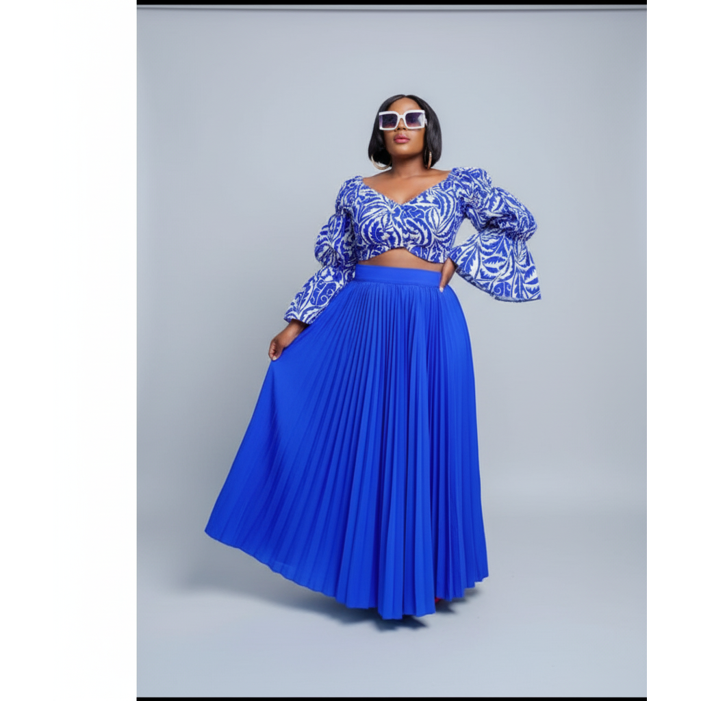 Woman wearing a blue and white patterned top with a long blue skirt on a gray background