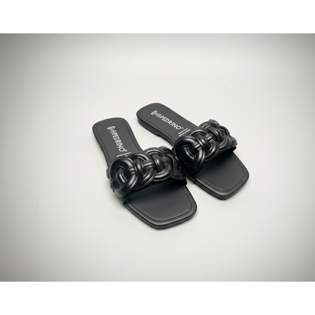 Black sandal with woven design on a light gray background