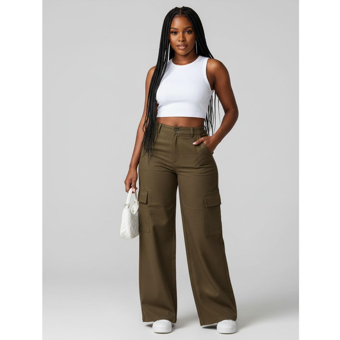 Woman wearing a white sleeveless top and olive green cargo pants on a gray background