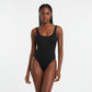 Woman wearing a black swimsuit against a plain background