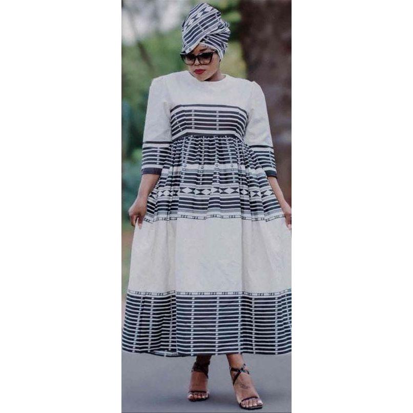 A woman wearing a traditional Xhosa round neck Ankara dress with three-quarter sleeves, featuring a geometric pattern.