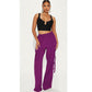Woman wearing a black crop top and purple high-waisted pants on a white background
