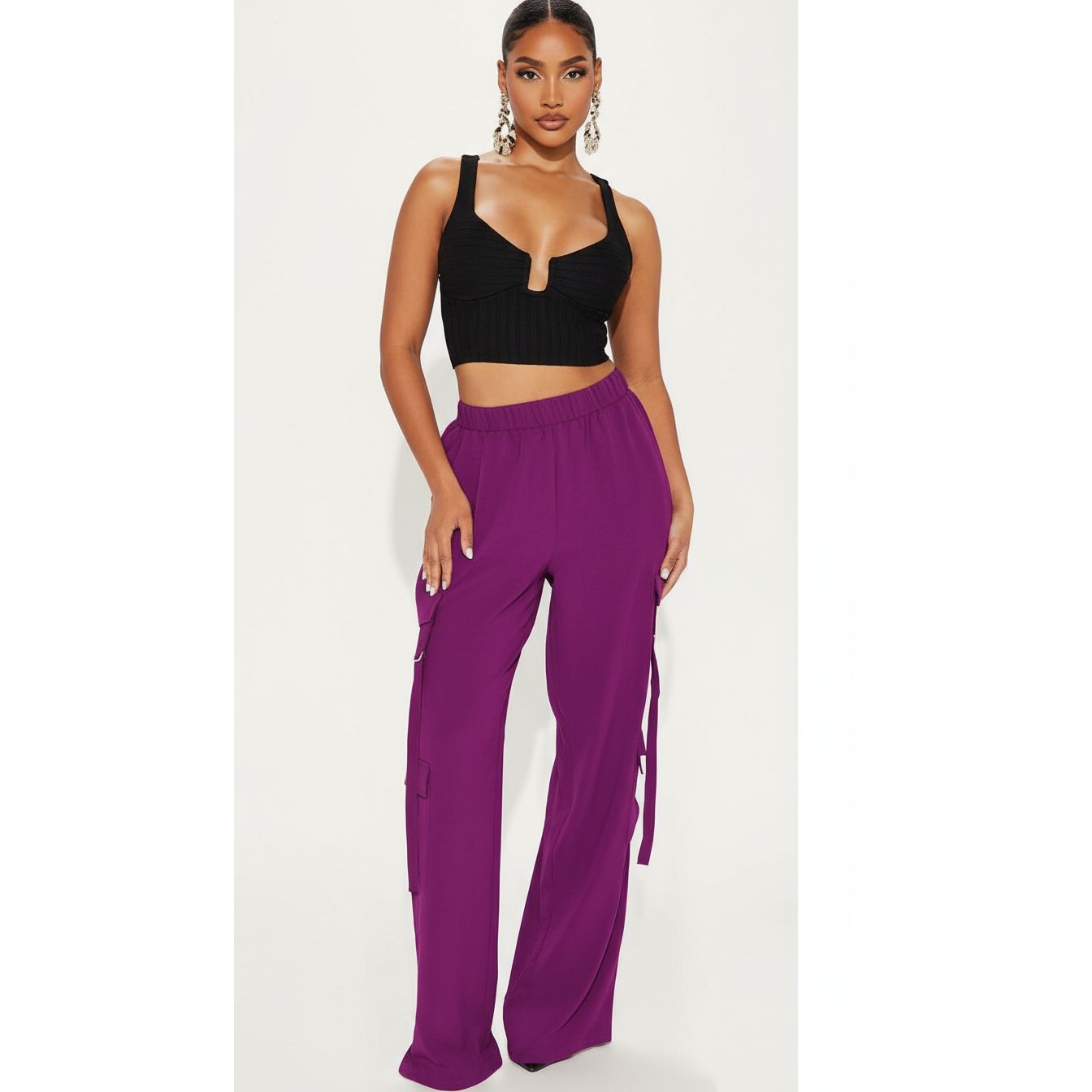 Woman wearing a black crop top and purple high-waisted pants on a white background
