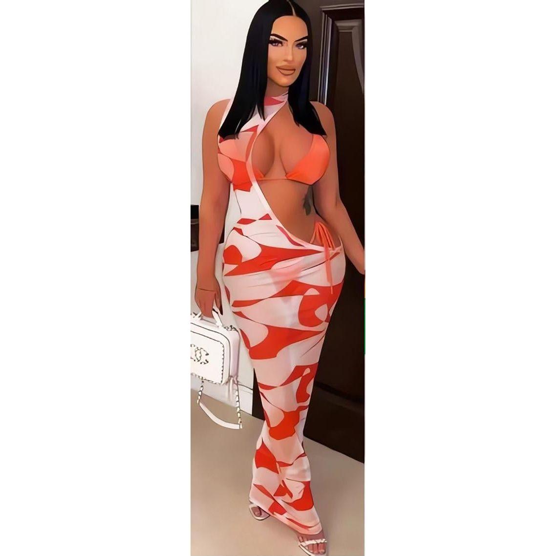 A model wearing a one-shoulder sleeveless long maxi swimwear dress with an allover print in red and white.