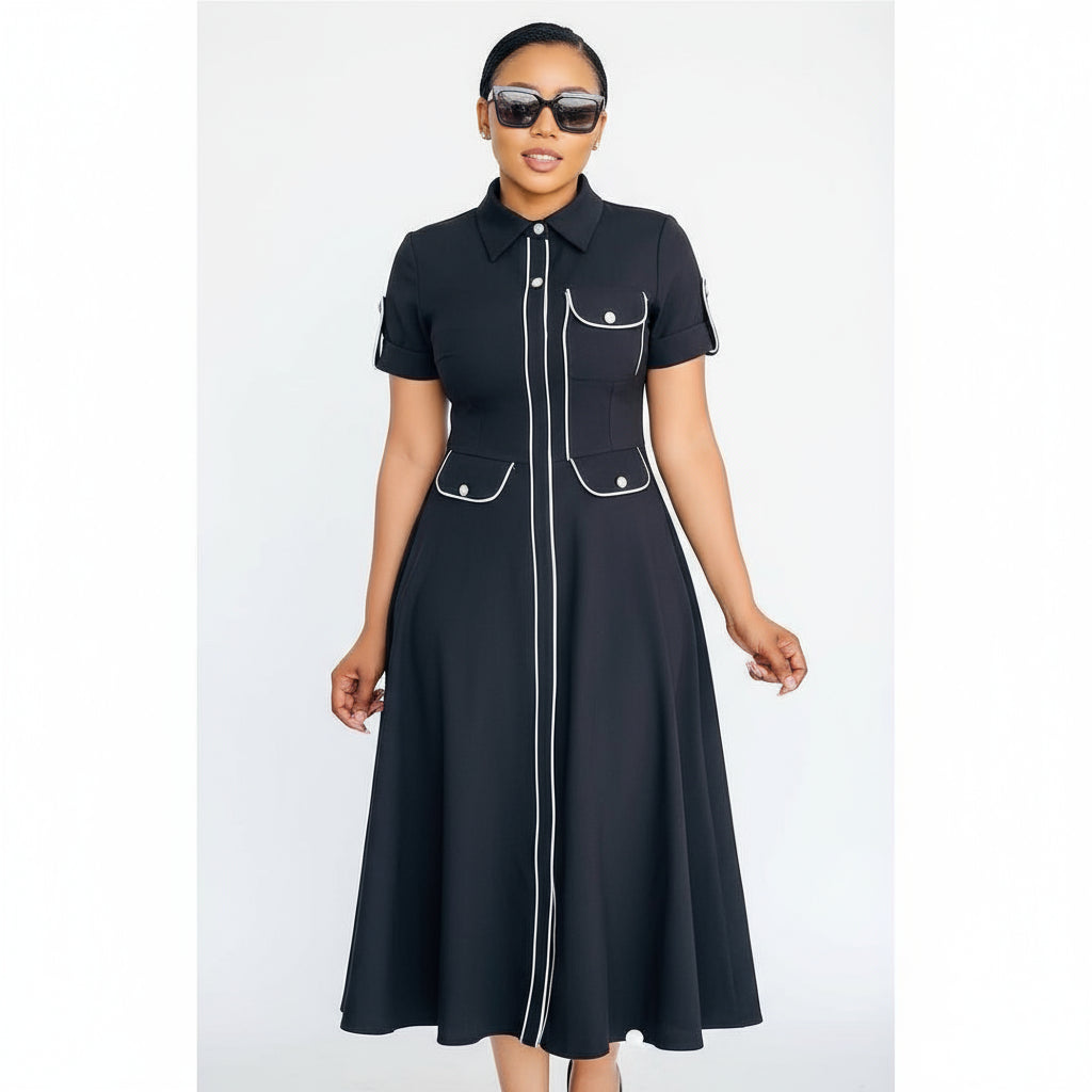 Woman wearing a black dress with white accents standing in front of a glass door.