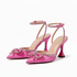 Pink high-heeled shoes with bow details on a white background