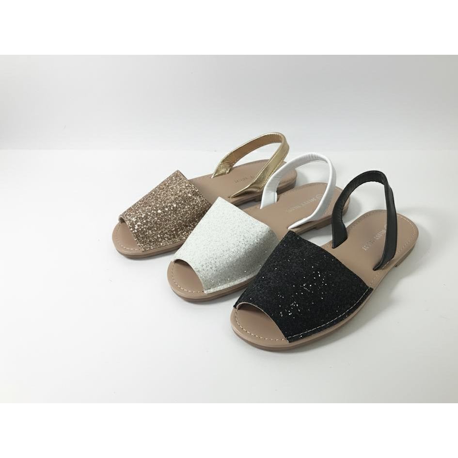 Three sandals in gold, white, and black on a light gray background