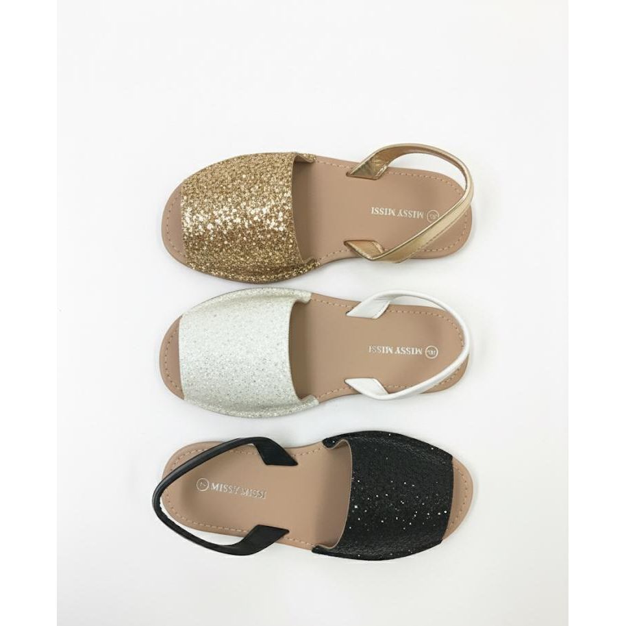 Three pairs of sandals in gold, silver, and black on a white background