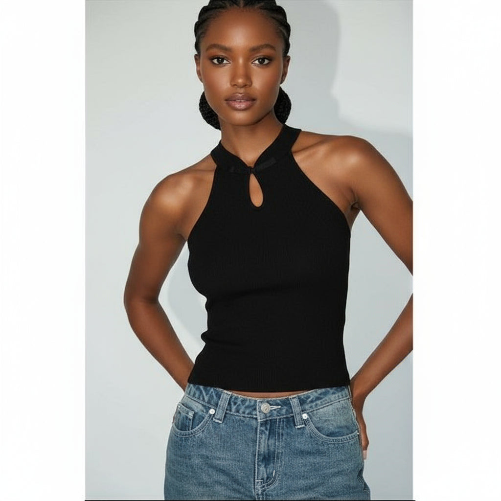 Woman wearing a black halter top and blue jeans against a plain background