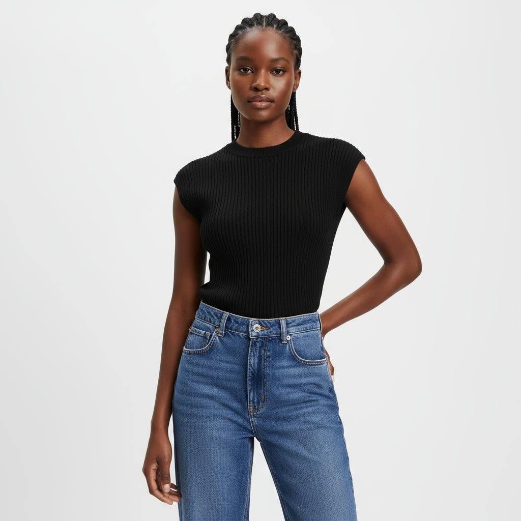 Person wearing a black ribbed tank top and blue jeans sitting on a wooden chair.