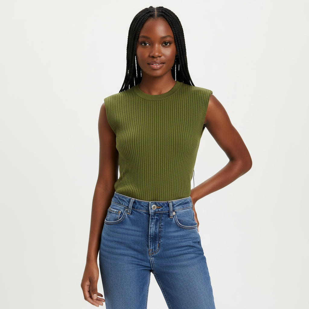 Person wearing a green ribbed crop top and blue jeans sitting on a wooden chair.