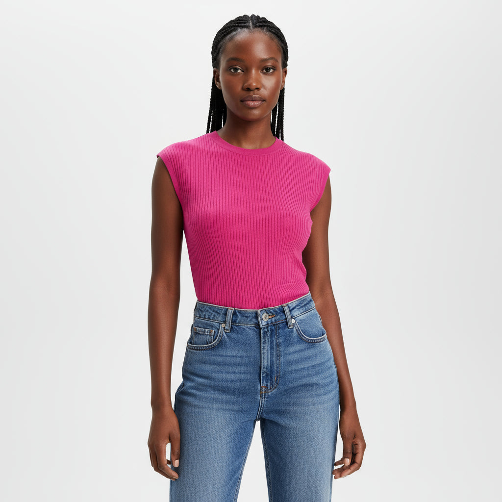 Person wearing a bright pink sleeveless top and blue jeans sitting on a wooden chair.