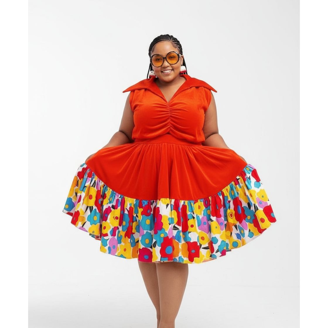 Woman wearing a bright orange dress with a colorful floral skirt on a white background