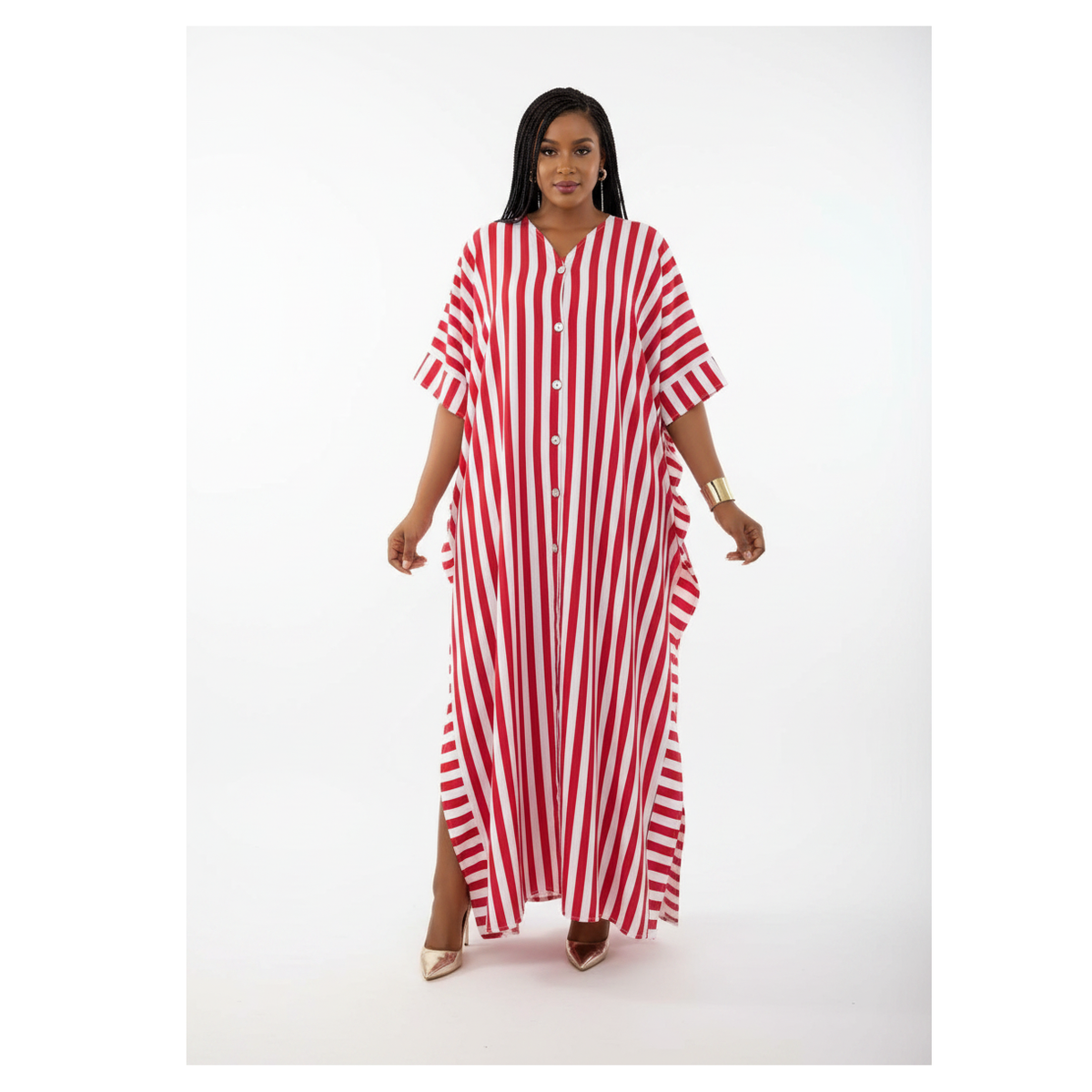 A woman modeling a red and white vertically striped kaftan dress with a button-down front and side slits, photographed against a seamless white studio background.