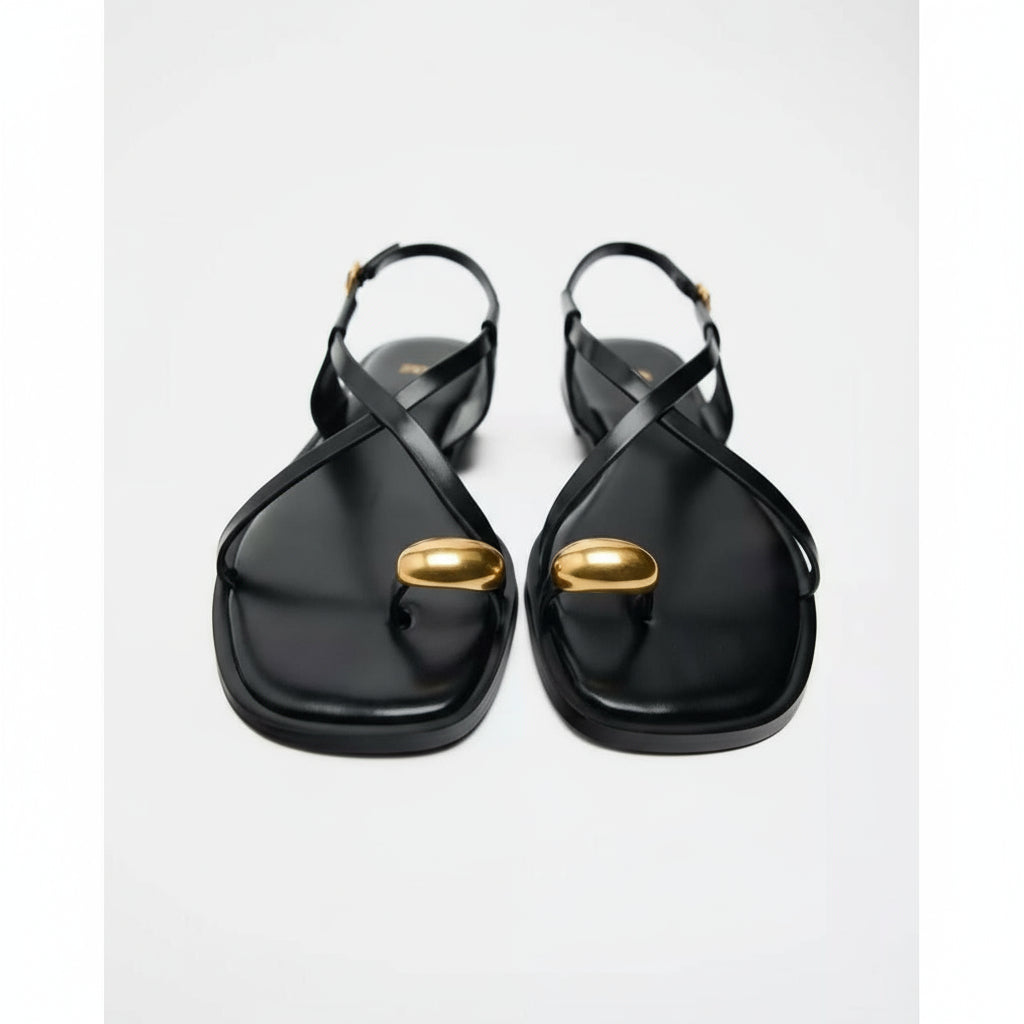 Black sandals with gold accents on a white background