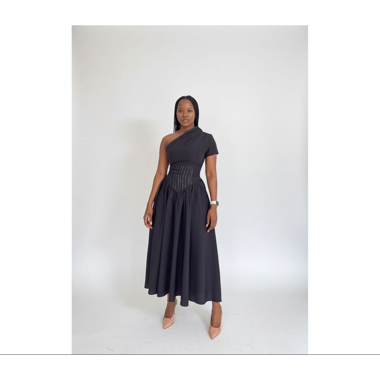 Woman wearing a black one-shoulder dress against a white background