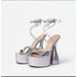 A pair of silver, thick heel platform ankle strap shoes with open toes and tied ankle straps.