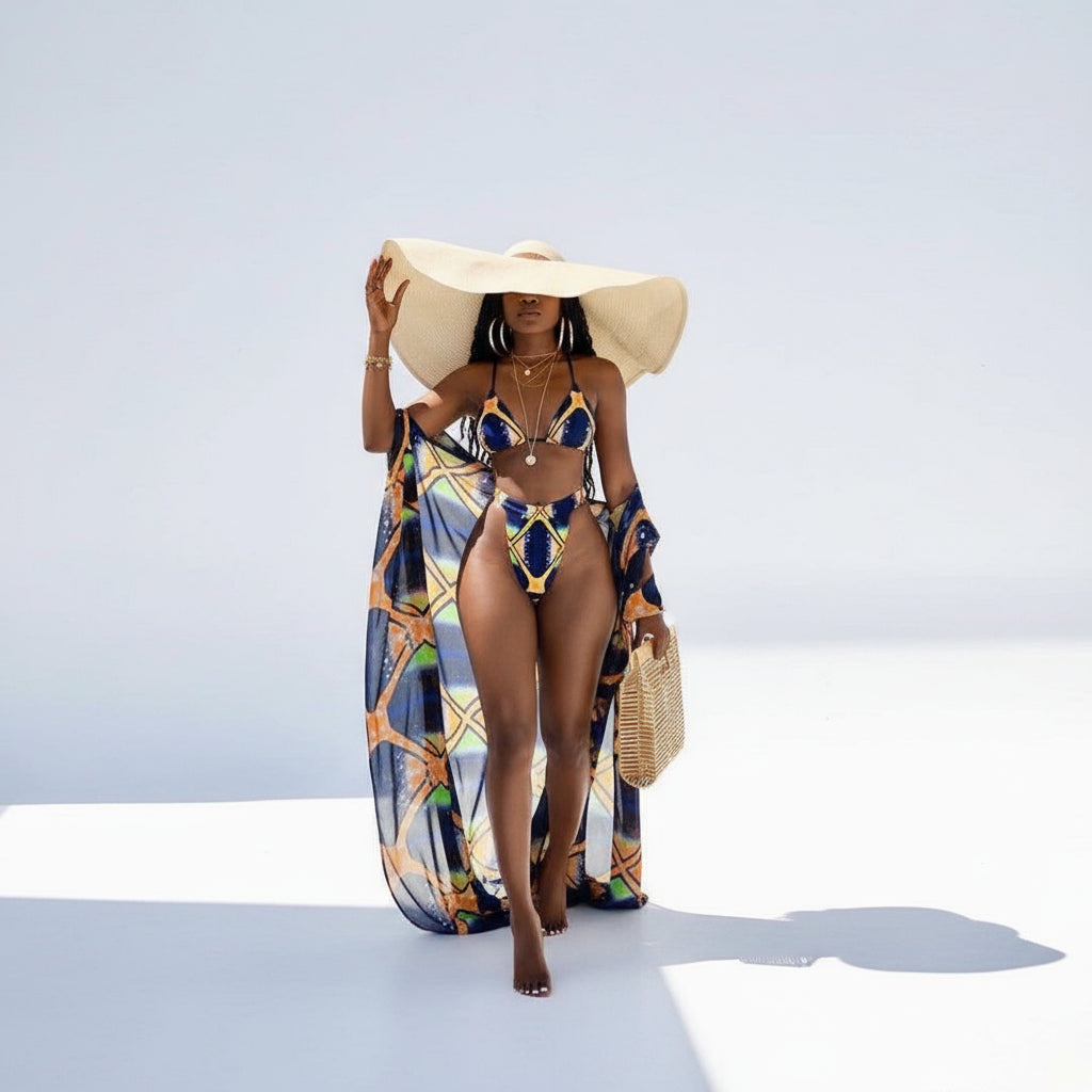A model wearing a multicolor geometric patterned swimsuit with a long kimono cover-up and a wide-brimmed hat.